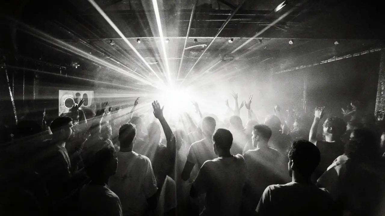 Underground warehouse party with strobe lights and a crowd immersed in techno music under laser beams.